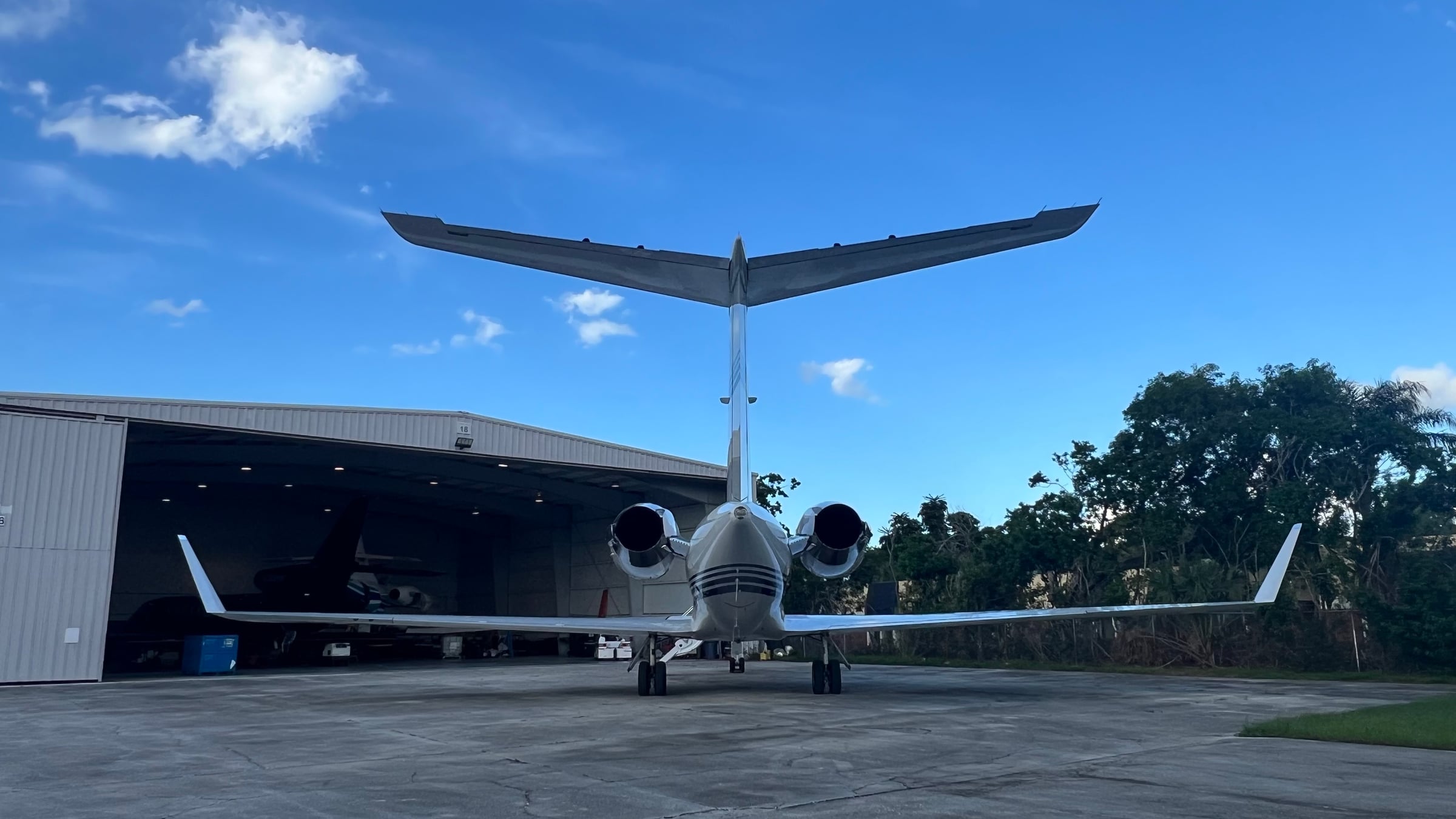A private jet outside Hangar 18 beneath a clear Florida sky